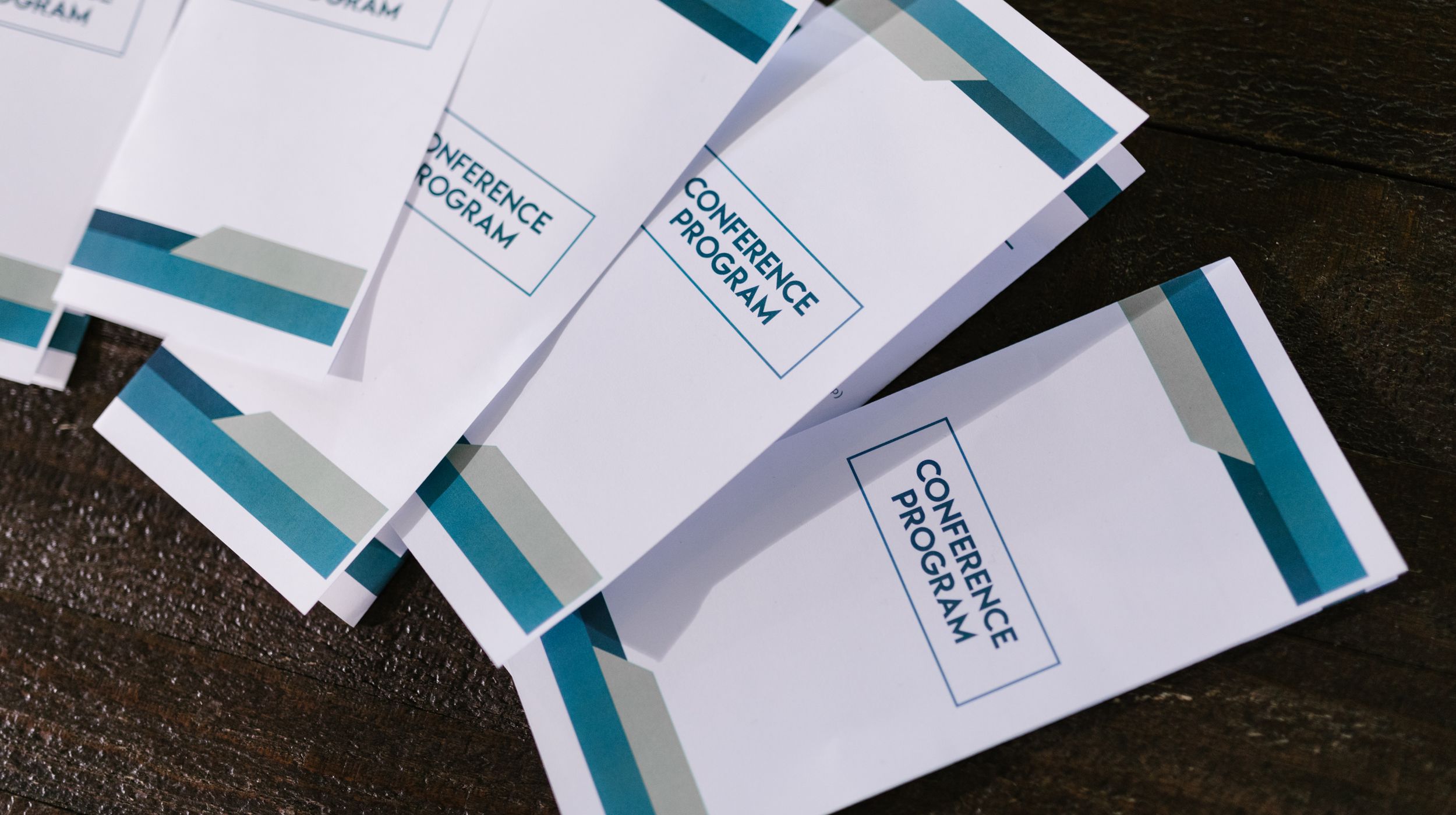 Several printed conference-program pamphlets fanned out on a wooden table.