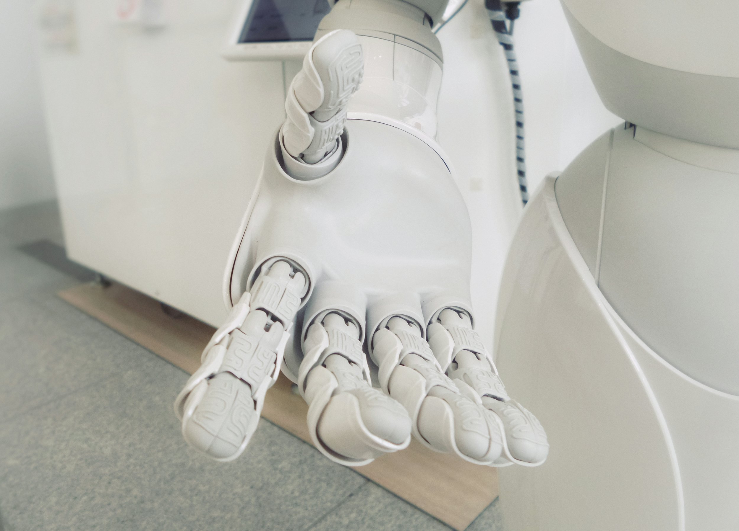 A close-up of a white humanoid robot's outstretched articulated hand.